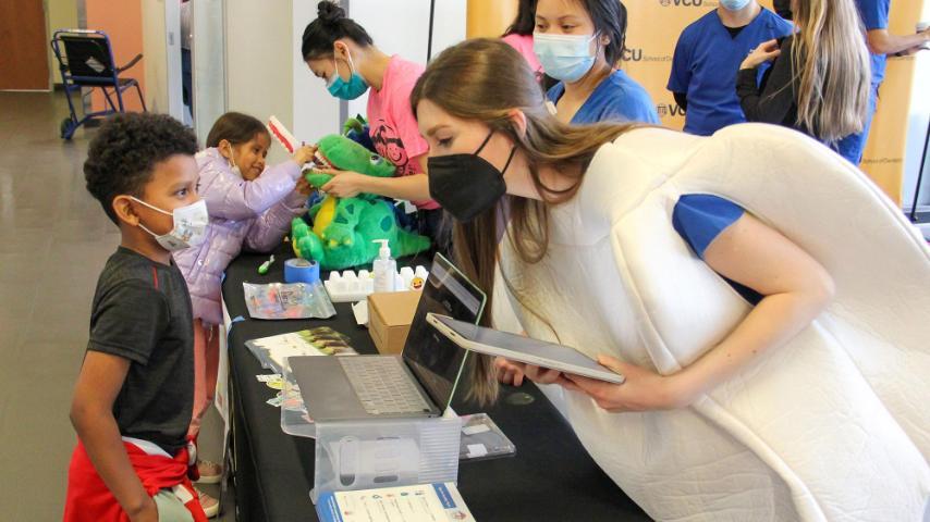 Student in tooth costume helping a kid during Give Kids a Smile